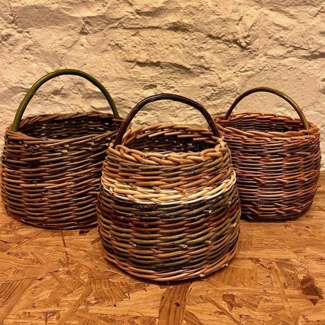 Three berry baskets sat on a wooden shelf against white wall.