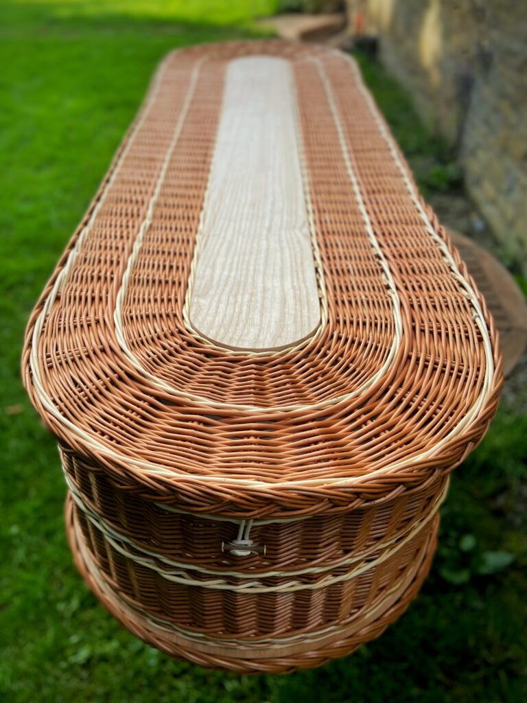 Looking down on the lid and rounded front of a buff willow coffin