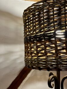 Light shining through a brown willow lampshade, showing off the zig-zag weave and French rand detail.