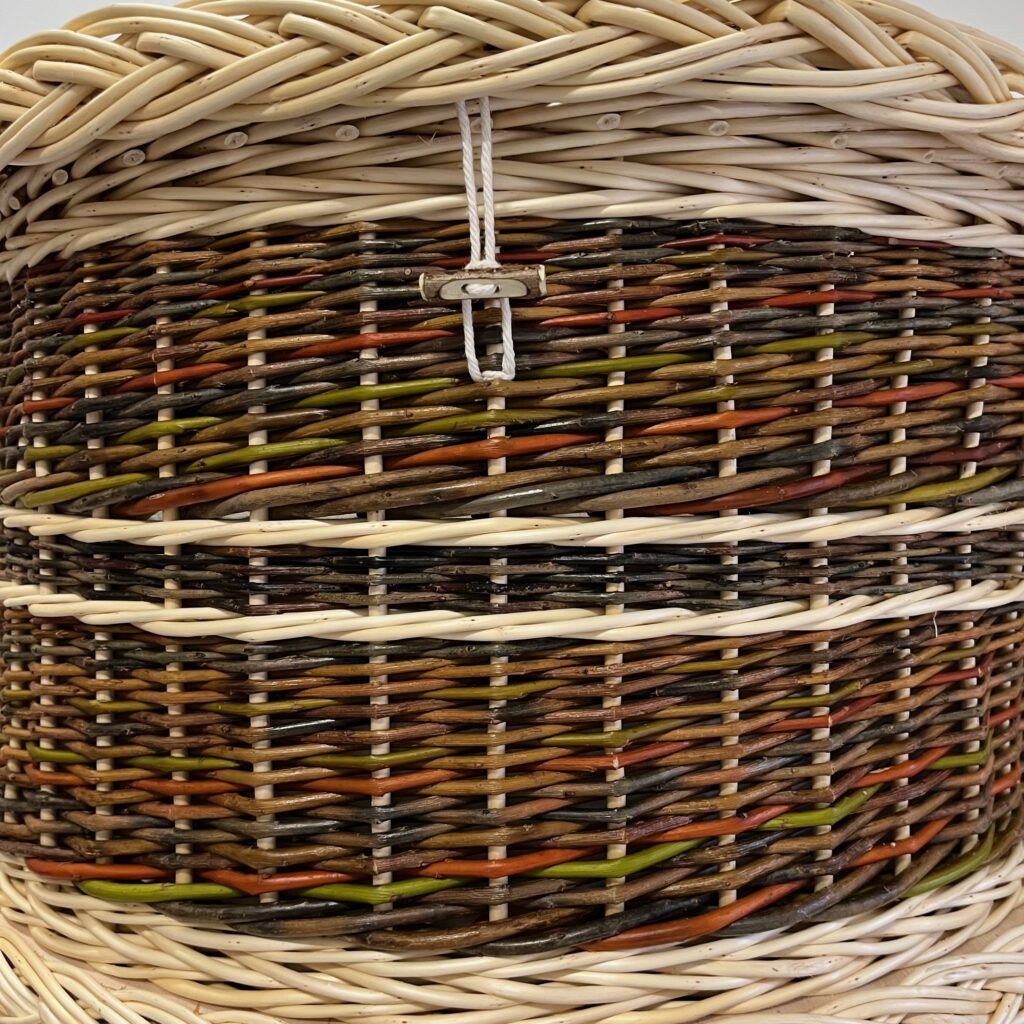 Zoomed in end view of colourful willow coffin with hazel toggle detail