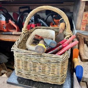 Square tool basket filled with hammer, nails and other tools on a work bench