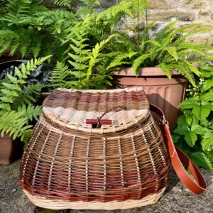 Colourful fishing creel basket in front of green ferns