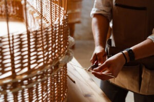 Hands cutting ends of willow next to a willow coffin