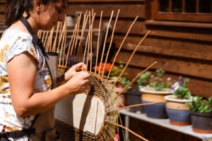 Steph stood outside weaving a coffin lid vertically in work stand